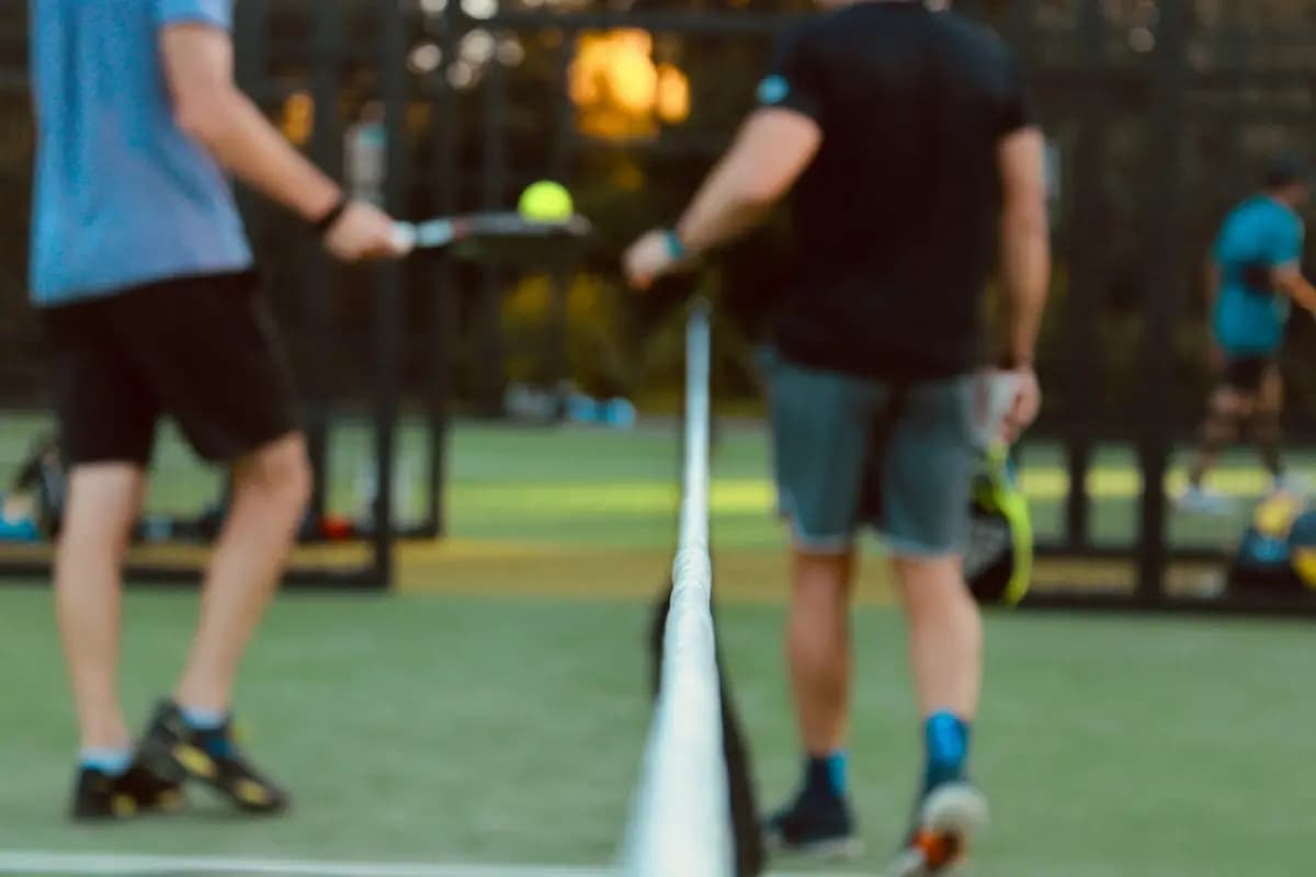 Close-up of a padel court with two padel players around the net.